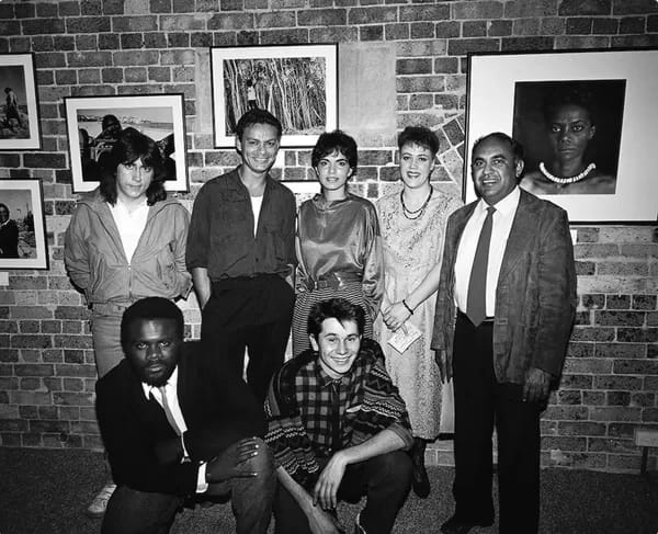 OzPhoto008-600 - 1EarthMedia NADOC 86 Exhibition of Aboriginal and Islander Photographers, Aboriginal Artists Gallery, Sydney, 1986. Back row: Darren Kemp, Michael Riley, Tracey Moffatt, Brenda L. Croft, Mervyn Bishop; front row: Tony Davis, Chris Robinson. Photograph by William Yang