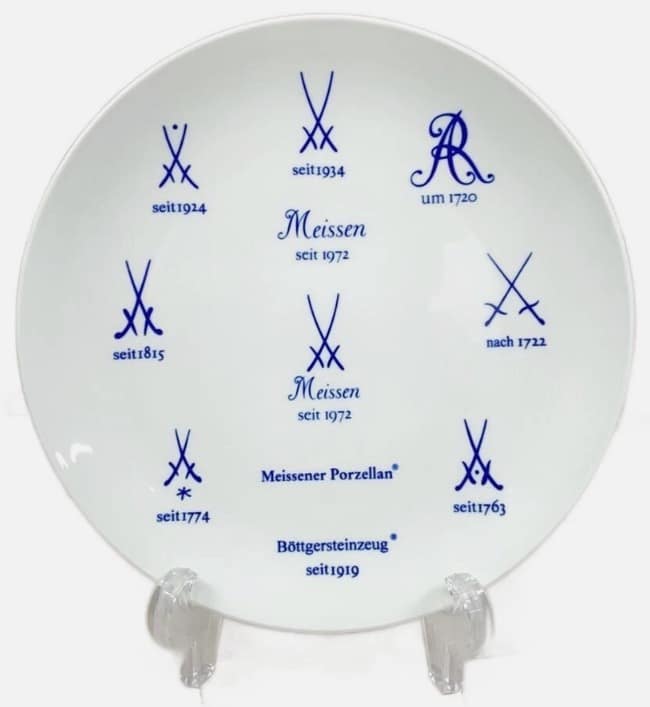 White ceramic plate showing multiple blue Meissen porcelain maker's marks and year labels arranged in a circle (e.g., seit 1972).