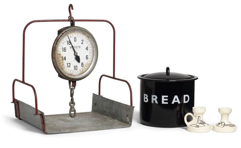 Diane Keaton kitchen - 1EarthMedia Vintage hanging platform scale with a circular dial beside a metal tray, next to a black bread canister and two cream-colored shakers.