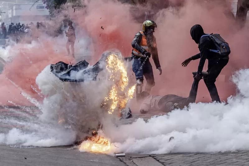 Africa Stories - Luis Tato Agence France-Presse - 1EarthMedia “The Cost of Protest” © Luis Tato, Agence France-Presse — used with permission World Press Photo Chaos unfolds outside Parliament on 25 June 2024, as tear gas clouds envelop two protesters carrying injured companions. The pain on their faces is unmistakable, etched into the air alongside the acrid smoke. The image forces the viewer to confront the human cost of political expression in a fragile democracy.